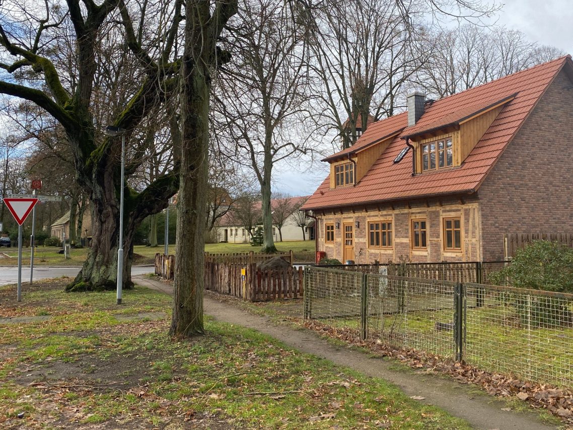Fachwerkhaus neu bauen mit Christianus_und-Paulsen Beratende Ingenieure Neues Fachwerkhaus mit rotem Dach, grünem Rahmen und unbebautem Grundstück.