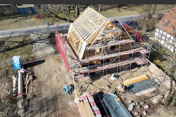 Bau eines Hauses mit Holzgerüst und Baustellengeräten im Freien.