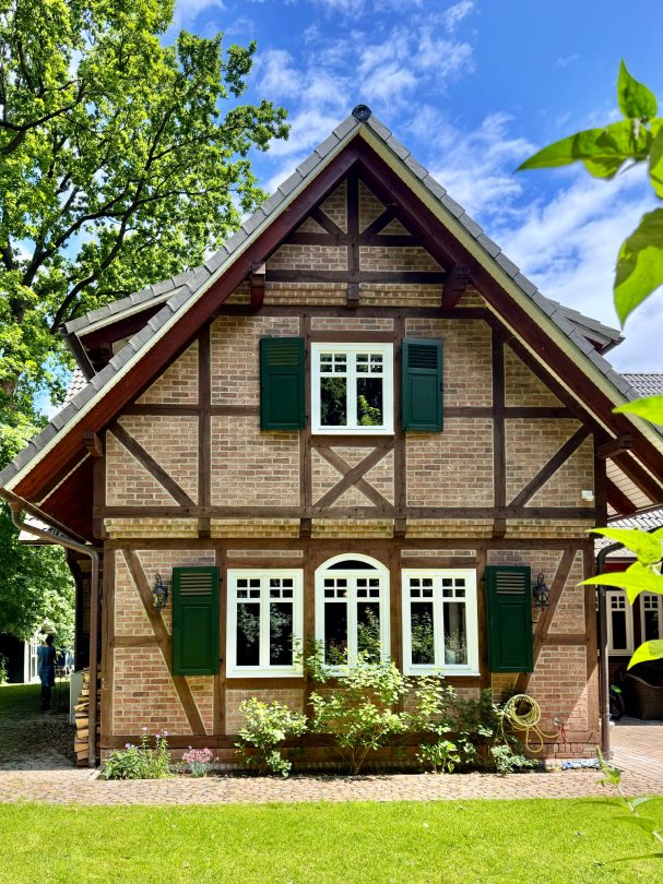 Fachwerkhaus mit Grünpflanzen, klarer Himmel und sonnigem Wetter im Hintergrund.