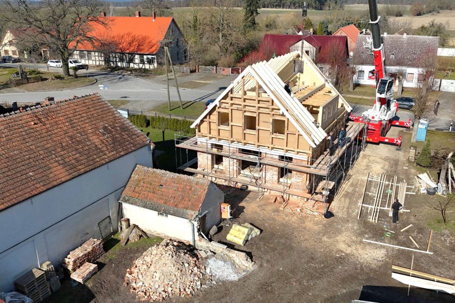 Neubau eines Hauses mit Holzrahmen und angrenzenden Nebengebäuden in ländlicher Umgebung.