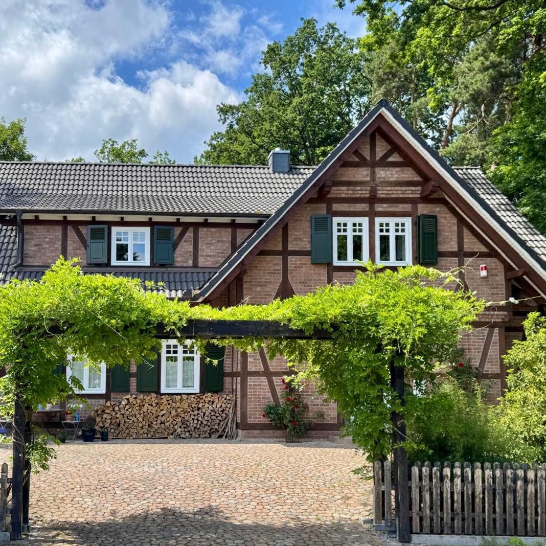 Fachwerkhaus- neu geplant Fachwerkhaus mit grünem Weinbewuchs und Garten, umgeben von Bäumen.