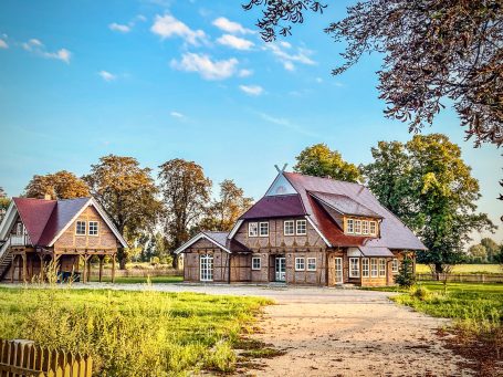 Schönes Holzhaus mit roten Dächern, umgeben von Bäumen und offenem Gelände.