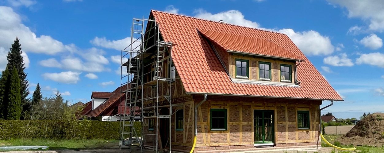 Rohbau eines Holzhauses mit Fachwerk aus Eichenholz und rotem Satteldach