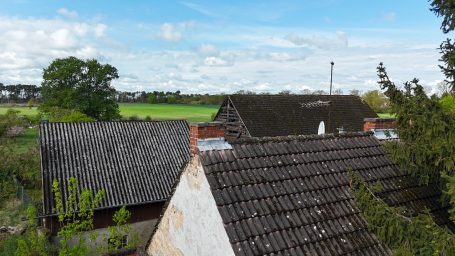 Dächer mehrerer Gebäude mit Landschaft im Hintergrund und blauem Himmel.