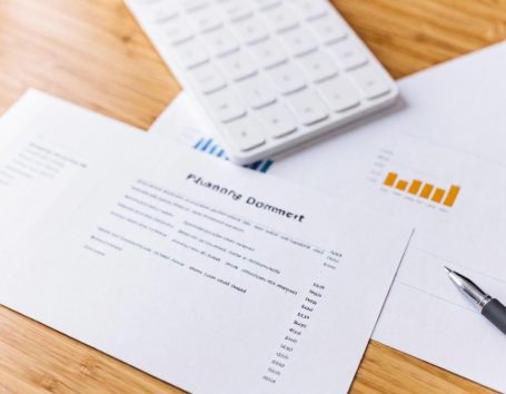 Finanzdokumente und Diagramme auf einem Holzuntergrund, Stift nebenan.