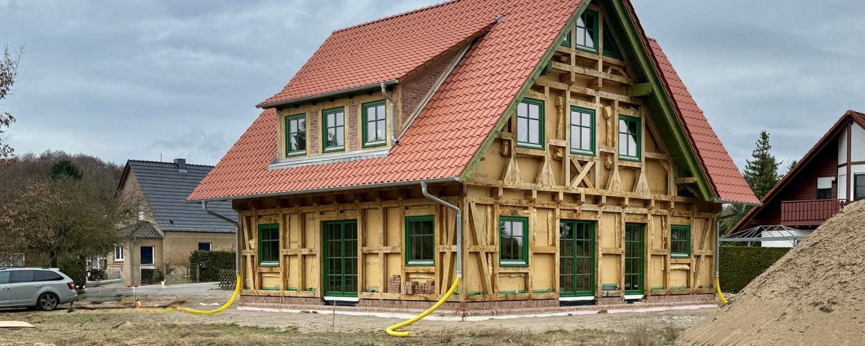 Rohbau eines Holzhauses mit Fachwerk aus Eichenholz und rotem Satteldach