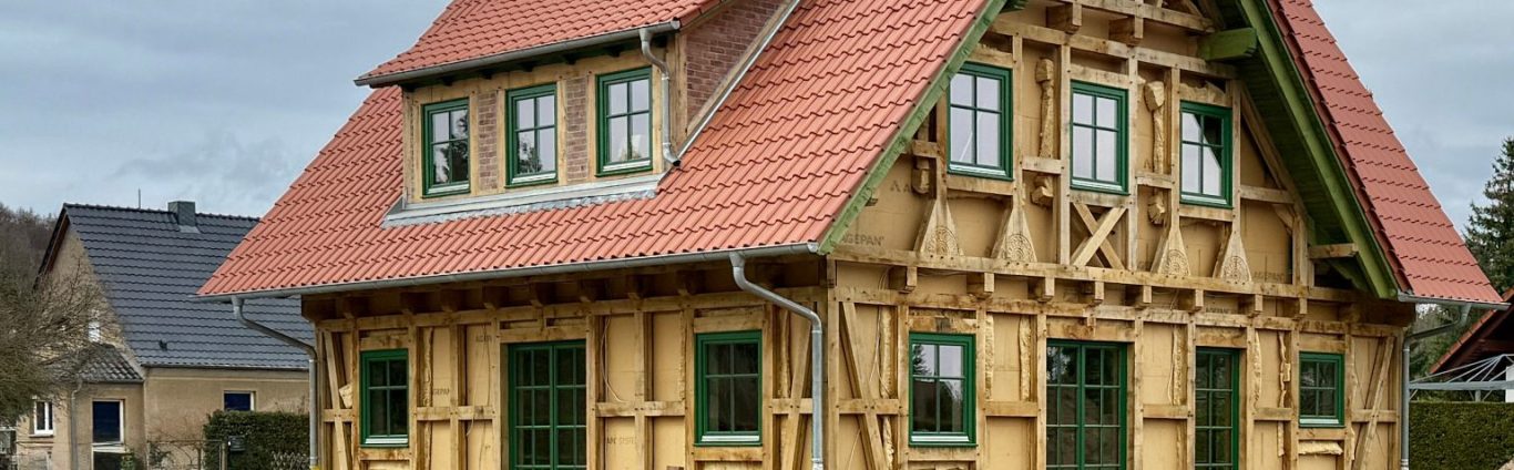 Rohbau eines Holzhauses mit Fachwerk aus Eichenholz und rotem Satteldach